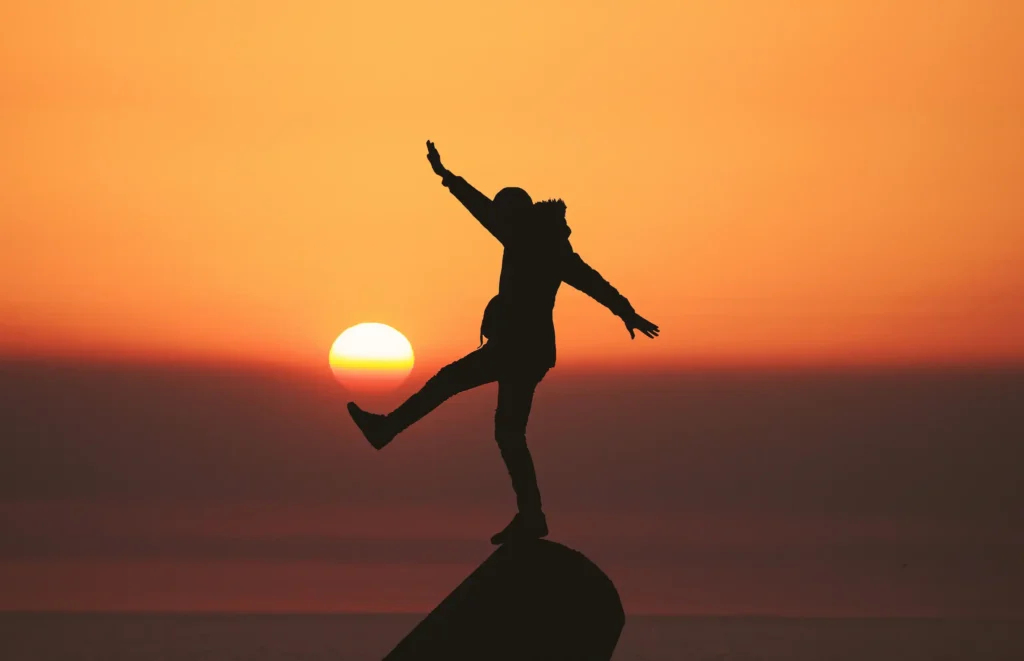 newington-spine-and-joint-2 The silhouette of a person standing on a rock in front of a beautiful sunset.